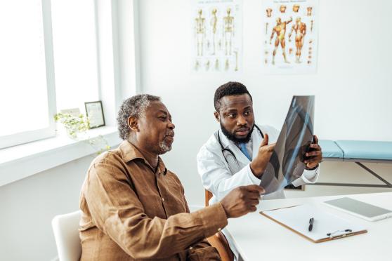 Doctor sharing and explaining X-ray results with senior man.